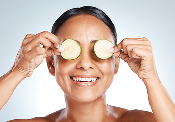 Image showing Cucumber, woman face and natural skincare, beauty or clean wellness on studio background. Happy model, eyes and green fruits cosmetics, detox and facial nutrition with vitamin c for healthy aesthetic