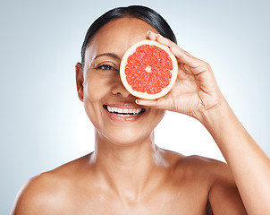 Image showing Grapefruit, woman and vitamin c beauty, portrait and skincare wellness on studio background. Happy model, face and citrus fruits for natural cosmetics, detox and nutrition for healthy aesthetic glow