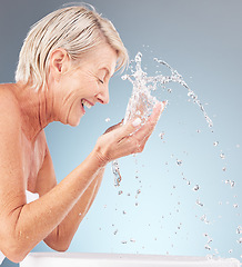 Image showing Senior woman, cleaning face and water splash on studio background for beauty, wellness and shower. Happy model, facial skincare drops and washing in bathroom for aesthetic, cosmetics and healthy body