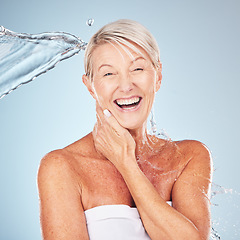 Image showing Smile, shower and portrait of a woman with a water splash isolated on a blue background in studio. Grooming, hygiene and face of an excited senior model with body and self care on a backdrop