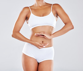 Image showing Wellness, gut health and hands on stomach of woman in studio for nutrition, healthy eating and digestion. Fitness, body care and abdomen of female model for diet, lose weight and detox treatment