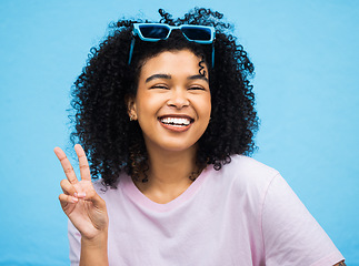 Image showing Black woman, happy smile and peace sign portrait of a model isolated with blue background in a studio. Young, smiling and v hand gesture of a person feeling relax with happiness with casual style