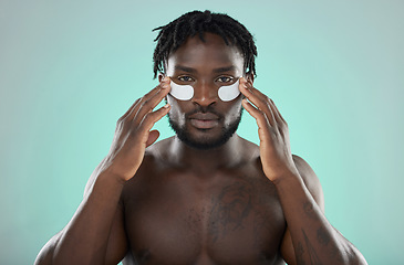 Image showing Skincare, eye pads and black man in studio for healthy, cosmetic and natural face routine. Health, wellness and portrait of an African guy with a facial treatment by blue background with mockup space