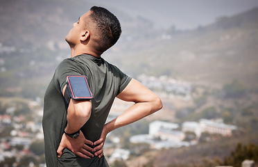 Image showing Fitness, pain and man with hands on back, hurt muscle on run with smartphone running tracker. Health, exercise and outdoor workout, runner with injury, tension or painful muscles on marathon training