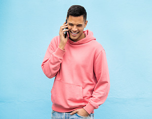 Image showing Casual man, phone and laughing on call in communication standing isolated on a blue background. Happy male, person or guys with pink jacket in discussion, conversation or talking on mobile smartphone