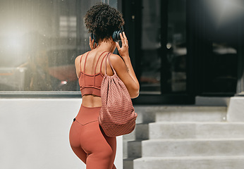 Image showing Fitness, headphones or personal trainer walking to gym listening to music to start a workout, exercise or training. Sports girl, back view or healthy black woman traveling or streaming radio audio