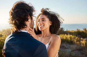 Image showing Marriage, wedding and bride with groom on by ocean for ceremony, commitment and celebration of love. Romance, happiness and interracial couple bonding, hug and smile on mountain, nature and outdoors