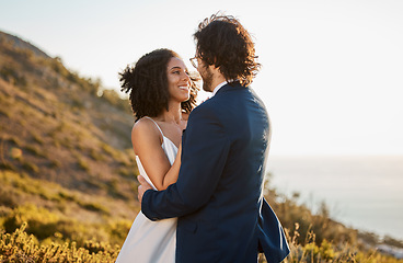 Image showing Marriage, love and bride with groom on mountain for wedding ceremony, commitment and celebration. Romance, happiness and interracial couple bonding, hug and smile with ocean, nature and outdoors