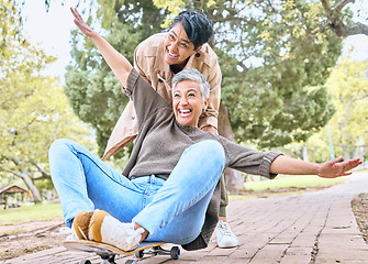 Image showing Senior women, park and couple of friends together outdoor for comic fun on a skateboard while happy. People together in nature for bonding, happiness and relax on retirement holiday with support