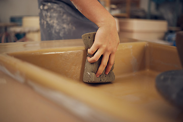 Image showing Hand, pottery and sponge with a woman in her workshop or studio to design or manufacture creative ceramic art. Manufacturing, product and cleaning with a female potter wiping a mold while sculpting