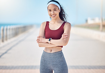 Image showing Happy woman, portrait and fitness with arms crossed at beach promenade for exercise, wellness and health in Miami. Female athlete, smile and standing at seaside for workout, summer training or sports