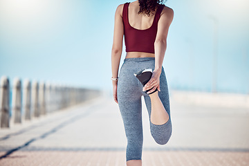 Image showing Fitness, woman and stretching legs at beach promenade for exercise, wellness and training. Back of athlete, runner and person warm up body at seaside for summer workout, sports and marathon running