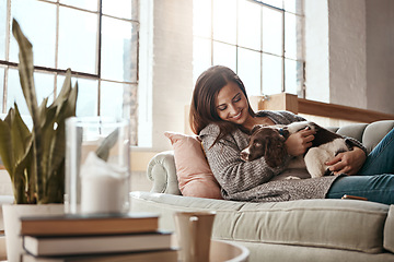 Image showing Woman relax on couch with puppy, happy and content at home with pet, happiness together with peace in living room. .Female cuddle dog, love for animals with smile and care, stress relief and comfort