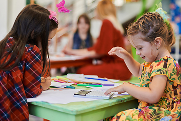 Image showing Creative kids during an art class in a daycare center or elementary school classroom drawing with female teacher.