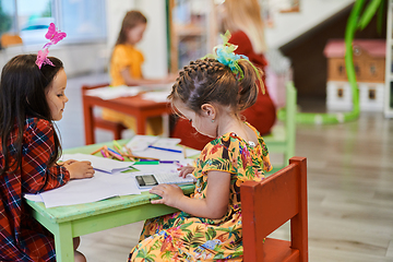 Image showing Creative kids during an art class in a daycare center or elementary school classroom drawing with female teacher.