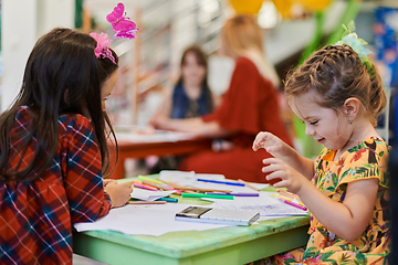 Image showing Creative kids during an art class in a daycare center or elementary school classroom drawing with female teacher.