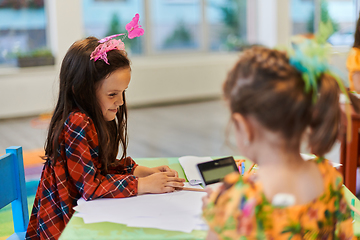 Image showing Creative kids during an art class in a daycare center or elementary school classroom drawing with female teacher.