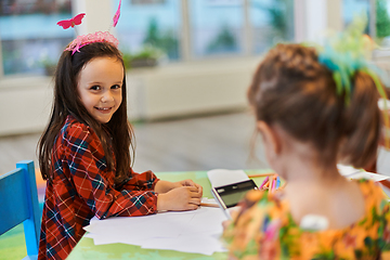 Image showing Creative kids during an art class in a daycare center or elementary school classroom drawing with female teacher.