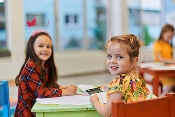 Image showing Creative kids during an art class in a daycare center or elementary school classroom drawing with female teacher.