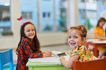 Image showing Creative kids during an art class in a daycare center or elementary school classroom drawing with female teacher.