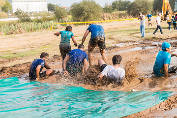 Image showing Athletes sliding to mud and water