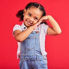 Image showing Little girl, cute and shy expression on isolated red background in fashion, trendy or cool clothes and curly hair. Smile, happy child and kid and innocent face, playful or blushing gesture on studio