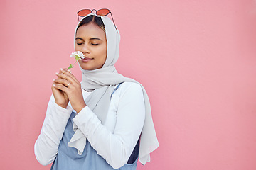 Image showing Young Islamic girl, smell flower and modern gen z or millennial fashion, zen freedom and calm peace in pink background. Muslim female, flowers scent and hijab with trendy or edgy clothes in studio