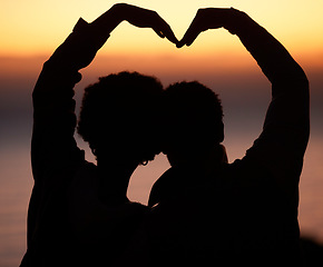 Image showing Sunset, heart and silhouette of couple at beach enjoying romantic vacation, holiday and honeymoon adventure. Emoji, travel and shadow of people relax, calm and together for trust, commitment and love