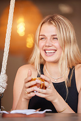 Image showing Happy, young and woman at cafe with coffee in cup and cheerful smile enjoying break at table. Laugh, youth and happiness of girl customer with drink at casual restaurant with bokeh light.