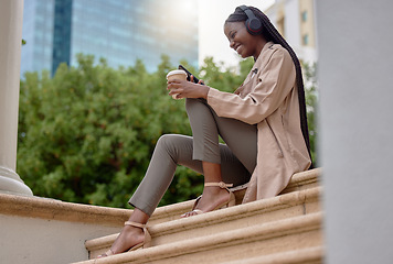 Image showing Music headphones, phone and black woman with coffee while sitting on city steps. Technology, tea break and happy female employee with caffeine and mobile for social media, streaming radio or podcast.
