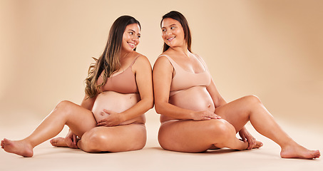 Image showing Women, bonding or sitting with pregnant stomach, tummy growth progress or baby healthcare wellness on studio background. Smile, happy or friends in pregnancy underwear for solidarity support or love