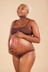 Image showing Pregnant, black woman and smile with flowers on belly in studio for body, baby wellness and ivf healthcare. Mother, pregnancy and floral plants on stomach with happiness, beauty or natural childbirth