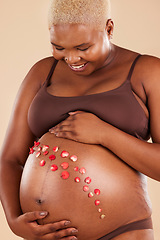 Image showing Pregnant woman, smile and flowers on stomach in studio, body and baby wellness of ivf healthcare. Mother, pregnancy and floral plants on abdomen of happiness, beauty or excited for natural childbirth