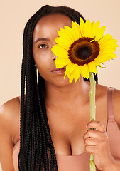 Image showing Portrait, beauty and sunflower with a black woman in studio on a beige background for natural treatment or body positivity. Spring, flower and skincare with a young female posing for wellness