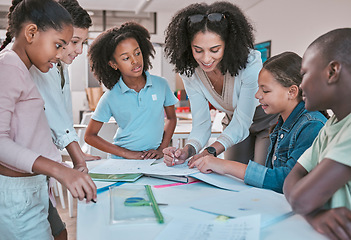 Image showing Female teacher in classroom with students, helping learner with homework and writing in book. Childrens education at school, educator reading kids notebook and group learning together for assessment