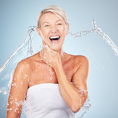 Image showing Skincare, grooming and portrait of an excited woman with a water splash isolated on a blue background in studio. Cleaning, hygiene and smile of a senior model with body and self care on a backdrop