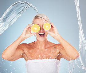 Image showing Water splash, studio and woman with lemon for wellness, healthcare or vitamin c by blue background. Happy senior model, citrus fruit and cosmetic skincare for happiness, excited or water drop on skin