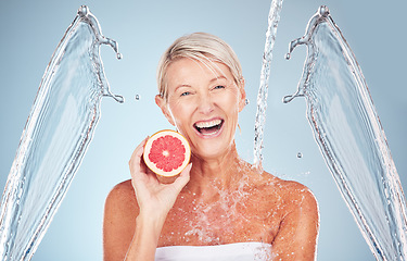 Image showing Woman, grapefruit and studio portrait with water splash, happiness and cosmetics for wellness by blue background. Senior model, citrus fruit and vitamin c for health, nutrition and self care process