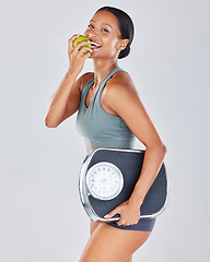 Image showing Portrait, scale and black woman eating apple on diet for weightloss, workout and health lifestyle. Fitness, nutrition and body wellness, healthy girl isolated on white background in studio with fruit