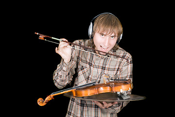 Image showing The young man in ear-phones eats a violin