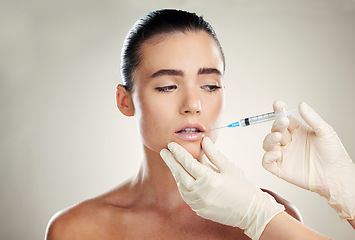 Image showing Skincare, beauty and woman with injection in lips from healthcare professional, anti aging wrinkle treatment in studio. Collagen, needle and model with facial lip filler syringe on white background.