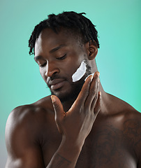 Image showing Black man with shaving cream, skincare product on face in studio background and smooth facial hair. Young african model grooming, male hygiene and cleaning beard with cosmetic morning routine