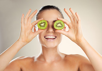 Image showing Kiwi fruit, skincare and cover beauty by a woman with natural dermatology cosmetic product. Healthy glow on face of aesthetic model in studio for sustainable spa facial mask for health and wellness