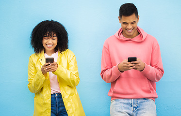 Image showing Happy couple, bonding and phone typing on isolated blue background on social media, dating app or travel networking. Smile, man or black woman on mobile technology or community communication website