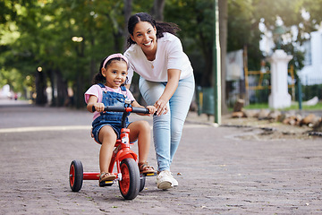 Image showing Mother, kid and bicycle teaching with training wheels for learning, practice or safety at the park. Happy mom helping little girl to ride a bike with smile for proud playful moments in the outdoors