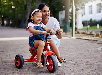 Image showing Mother, little girl and bicycle teaching with training wheels for learning or practice at the park. Happy mom helping child to ride her first bike with smile for proud playful moments in the outdoors