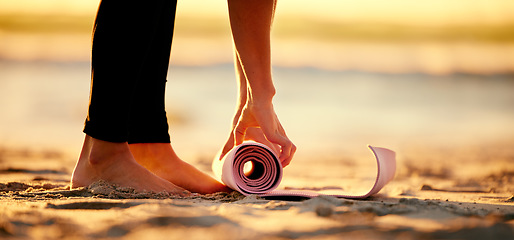 Image showing Hands, beach and woman roll yoga mat to start workout, exercise or stretching. Zen, meditation and feet of female yogi outdoors on seashore while preparing for chakra training, exercising and pilates