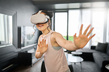 Image showing VR, metaverse and futuristic with a woman in the living room of her home using a headset to access a 3d game. Technology, virtual reality and gaming with a female gamer using ai to play online games