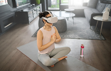 Image showing Virtual reality, meditation and fitness with a woman using a headset to access the metaverse in her home for health. VR, yoga and exercise with a young female yogi meditating in her house using 3d ai