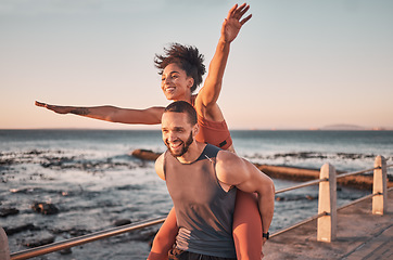 Image showing Sunset, relax and couple piggyback by ocean enjoying holiday, vacation and quality time on weekend. Love, freedom and happy black man and woman after exercise, fitness workout and training by sea